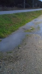 Estado de la calle, socavones y riachuelo tras lluvias.